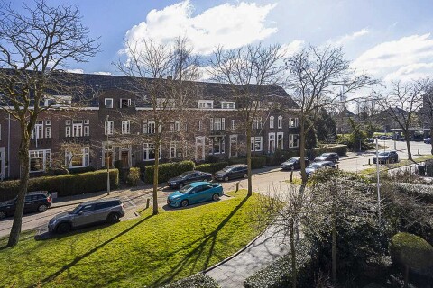 Karakteristieke jaren-20 woning in Rotterdam met bakstenen gevel, erker en glas-in-loodramen &ndash; perfect voorbeeld van historische stadsarchitectuur.